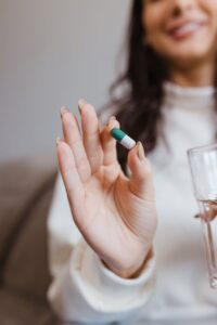 woman holding capsule and glass of water